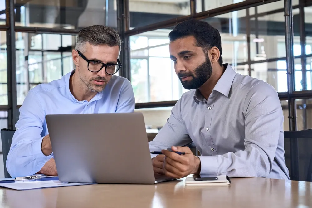 two business men hovering over laptop